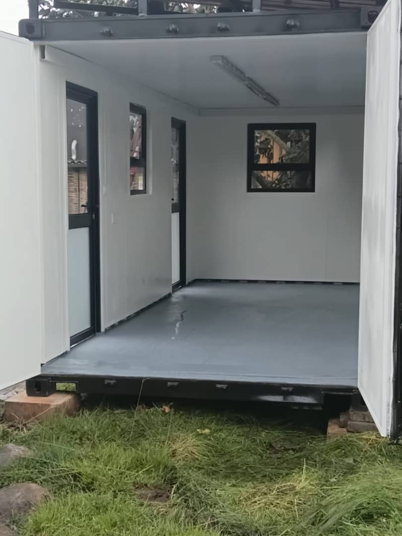 Open container interior showing finished wall panels, black-framed windows and floor